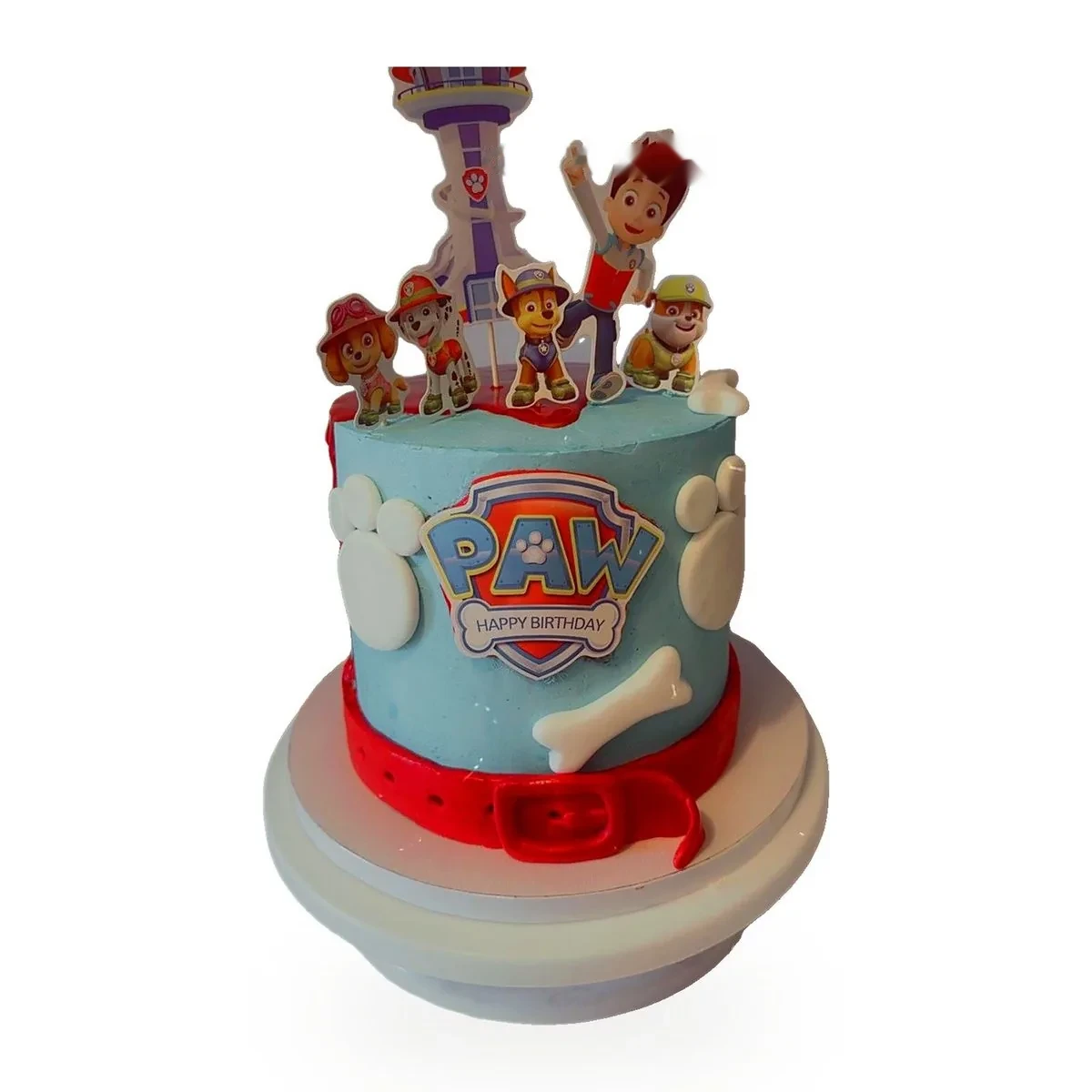 Gâteau Pat'Patrouille : crème bleue, écusson PAW Happy Birthday, empreintes et os blancs, collier rouge à boucle à la base, figurines de Ryder, Chase, Marcus, Stella et Ruben devant la tour de contrôle