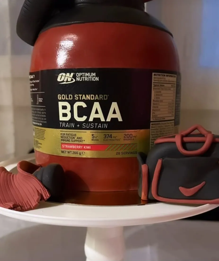 Gâteau trompe-l'œil en forme de pot de BCAA, avec un sac de sport en pâte à sucre à côté